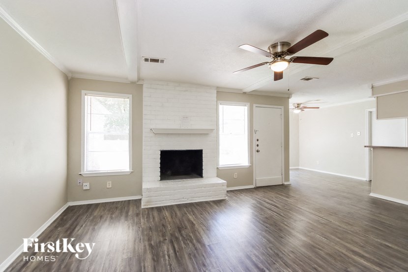 an empty living room with a fireplace and a ceiling fan
