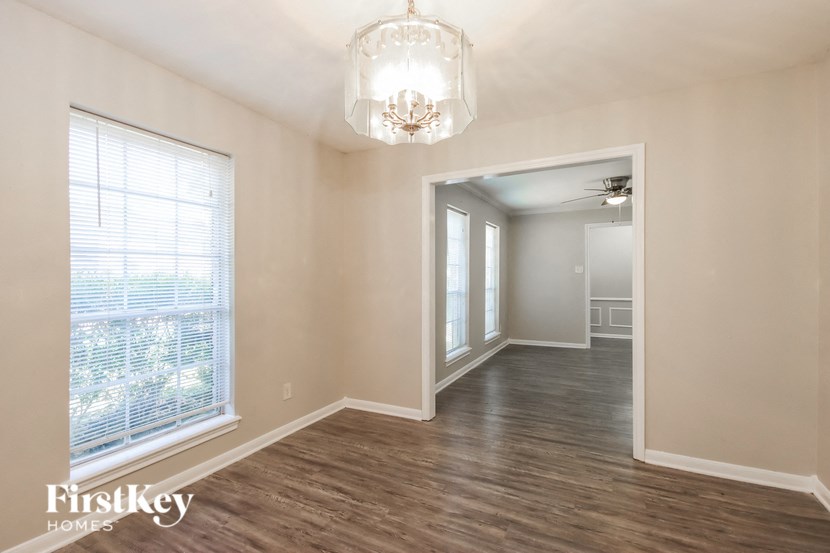 an empty living room with a large window and a chandelier
