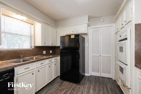 a kitchen with white cabinets and a black refrigerator