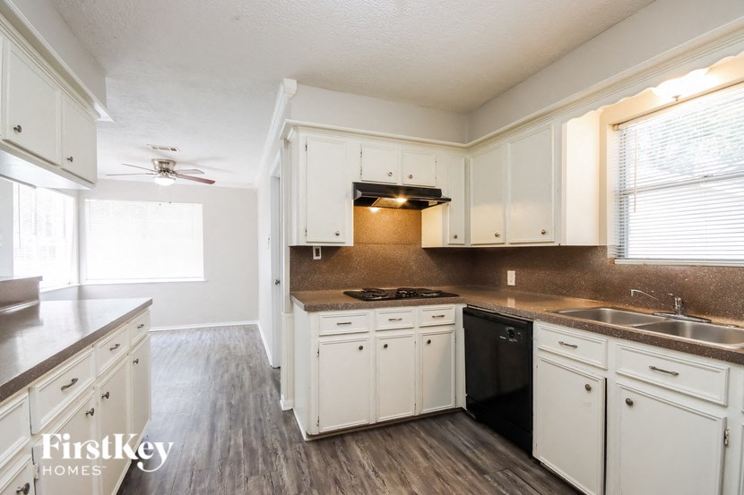 an empty kitchen with white cabinets and black appliances