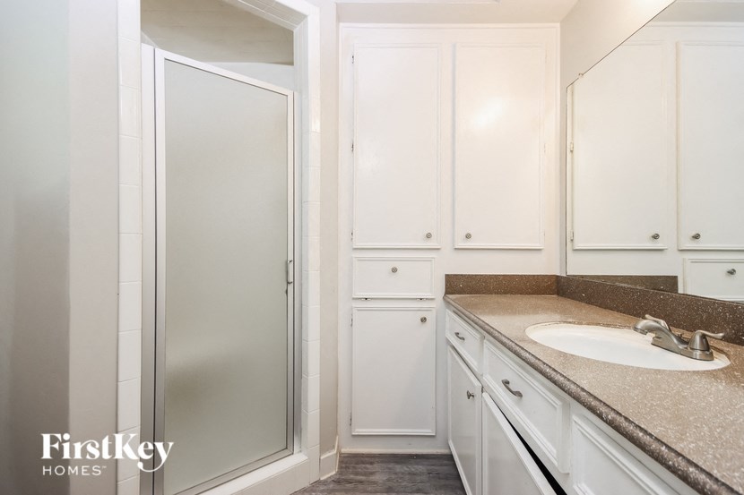 a bathroom with white cabinets and a sink and a shower