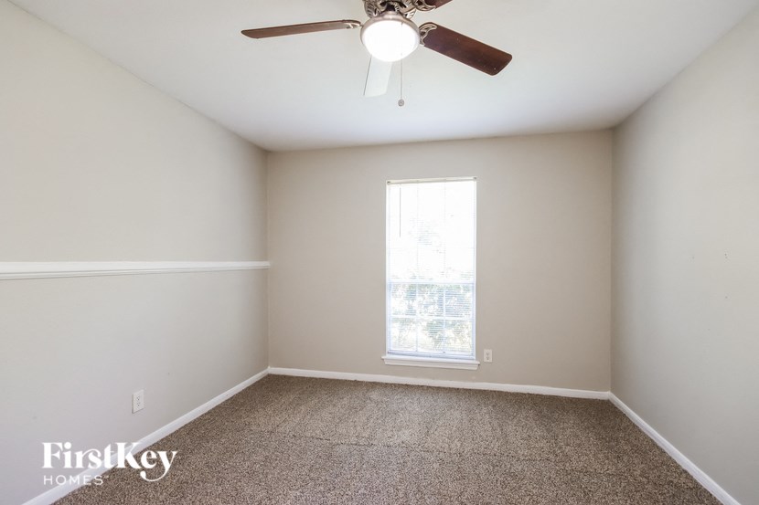 an empty room with a ceiling fan and a window