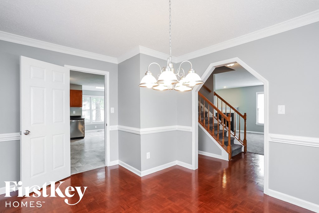 a dining room and living room with a staircase and a chandelier