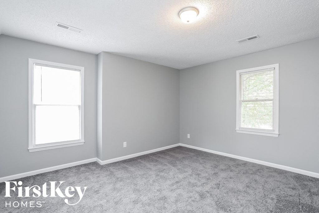 a bedroom with two windows and a carpeted floor