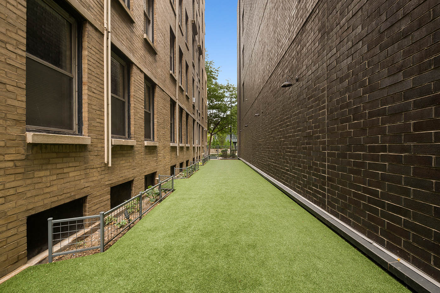 a green walkway between two brick buildings with grass