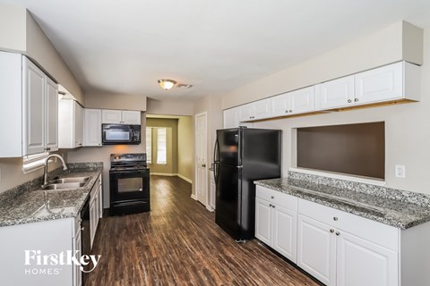 A kitchen with a black refrigerator and white cabinets.