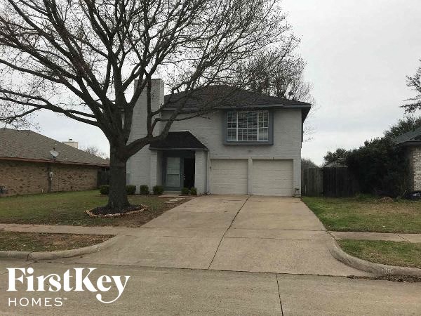a white house with a driveway and a tree