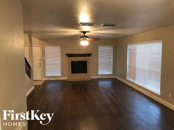 an empty living room with a fireplace and a ceiling fan