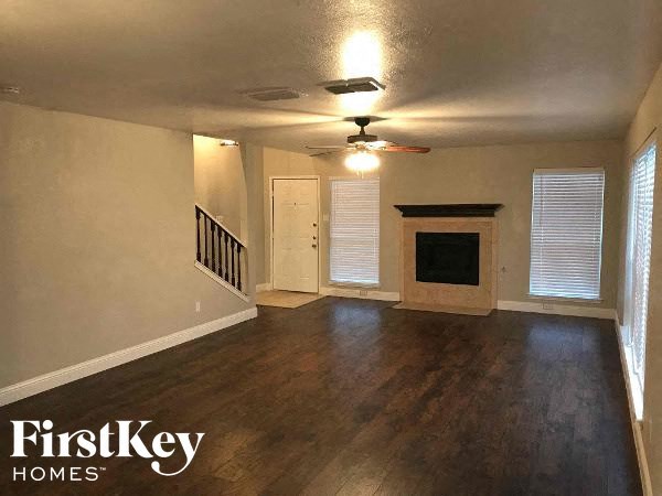 an empty living room with a fireplace and a ceiling fan
