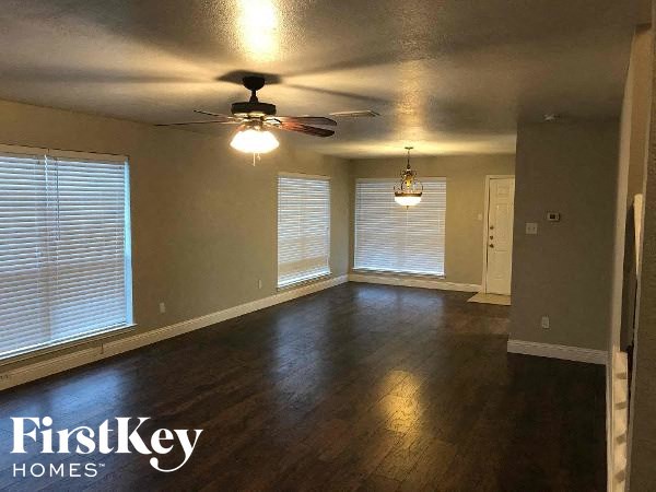 an empty living room with a ceiling fan and windows