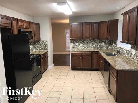 a kitchen with brown cabinets and a black refrigerator