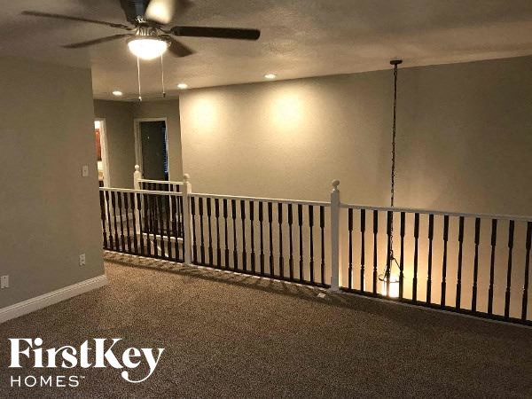 a living room with a railing and a ceiling fan