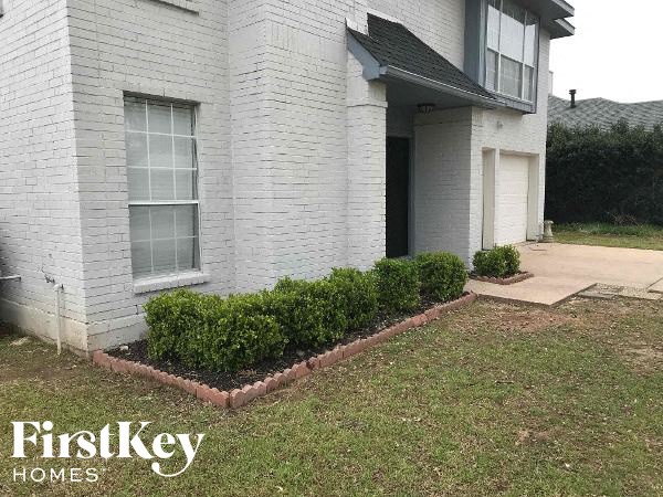 a white brick house with a front yard with bushes