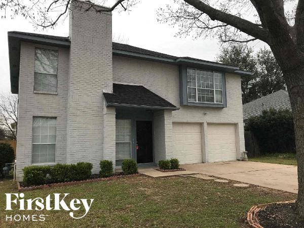 a white brick house with a driveway and a tree