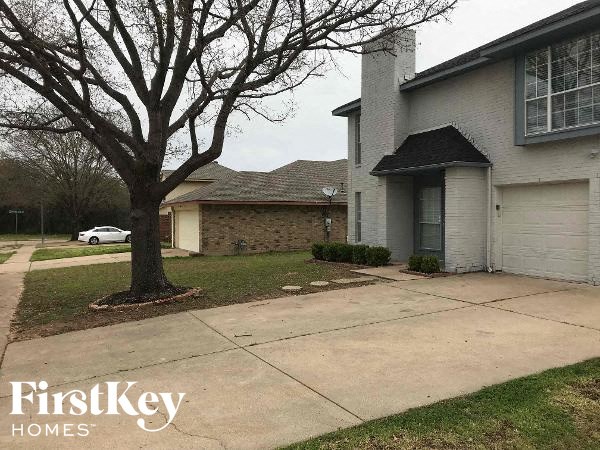 a sidewalk in front of a house with a tree