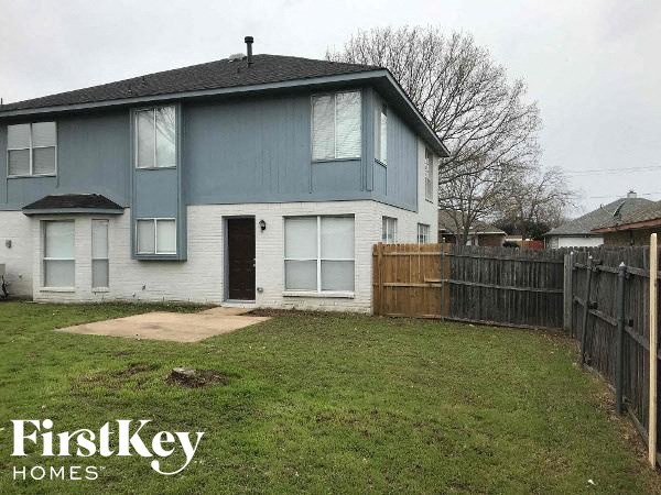 a blue and white house with a yard and a wooden fence