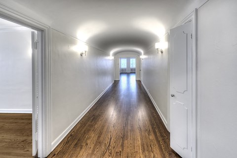 a long hallway with white walls and wood floors