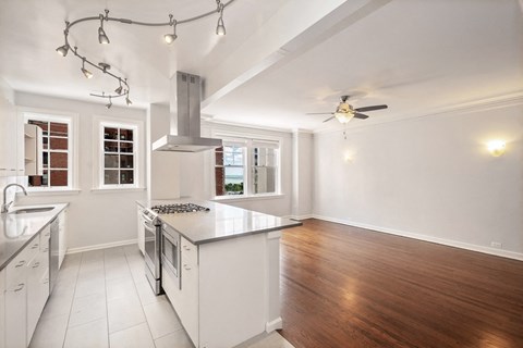 a kitchen with white cabinets and a white island and a ceiling fan