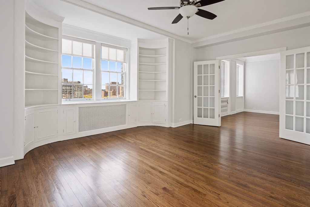 an empty living room with hardwood floors and a ceiling fan