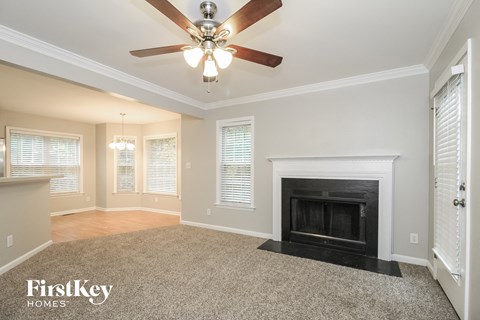 A spacious living room with a fireplace and a ceiling fan.