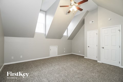 A spacious room with a ceiling fan and two doors.