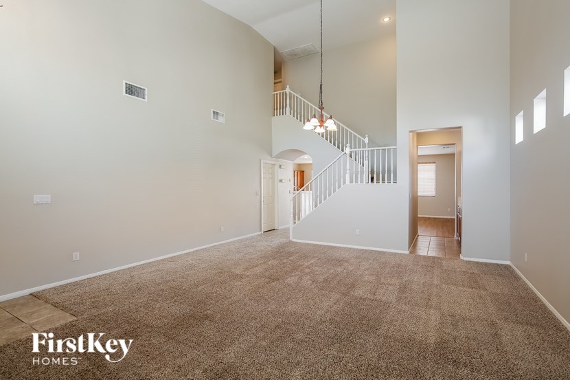 A spacious room with a carpeted floor and a staircase leading to another room.