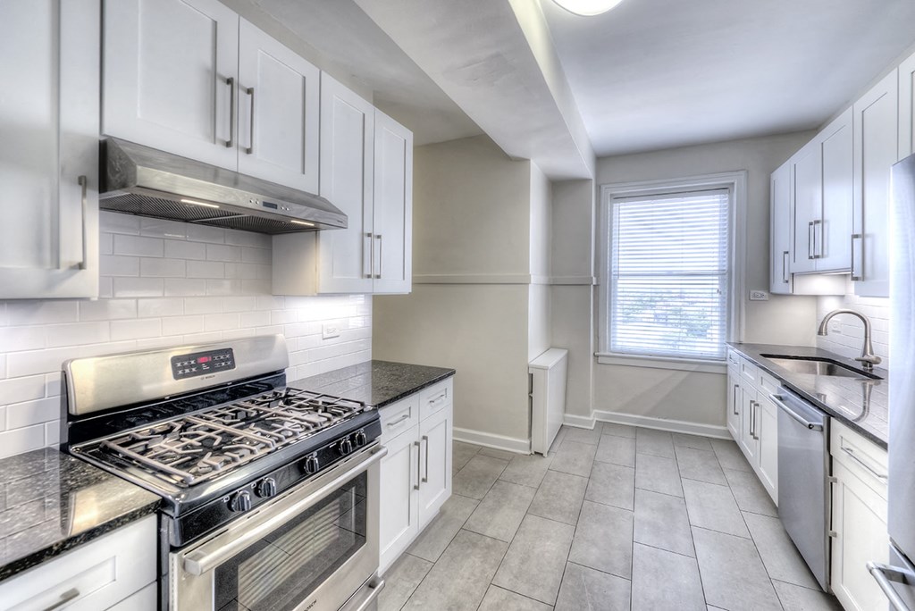 an empty kitchen with white cabinets and stainless steel appliances