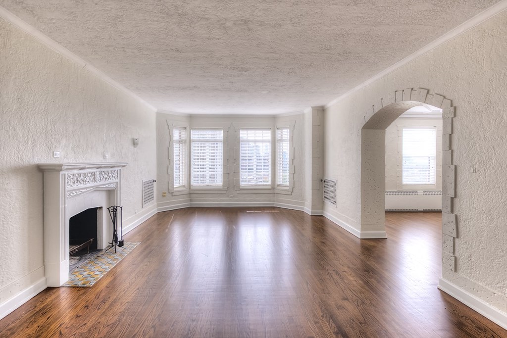 an empty living room with a fireplace and wooden floors