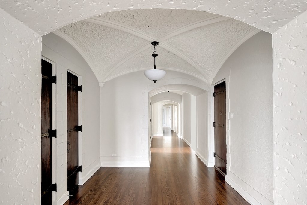 a hallway with white walls and wood floors and a white arched ceiling