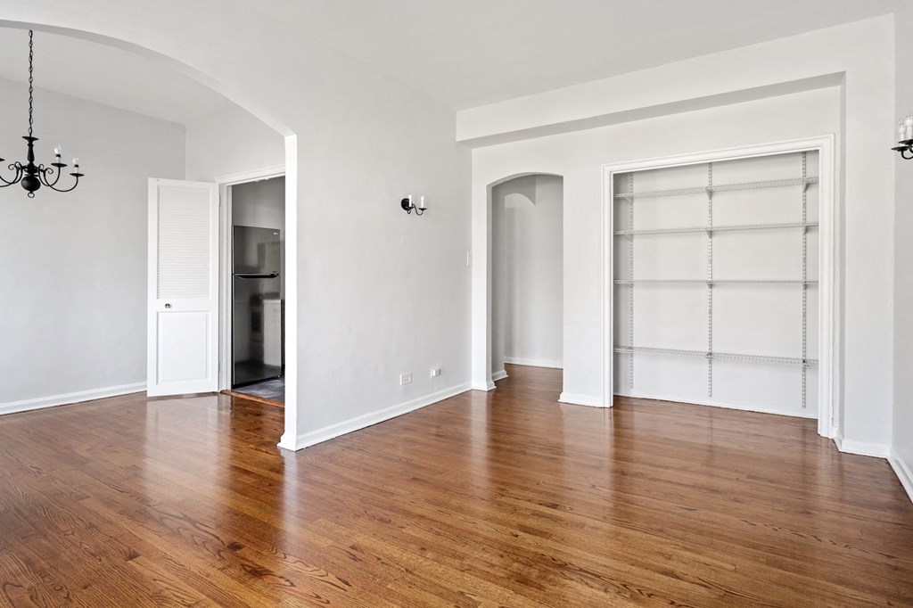 an empty living room with wood floors and white walls
