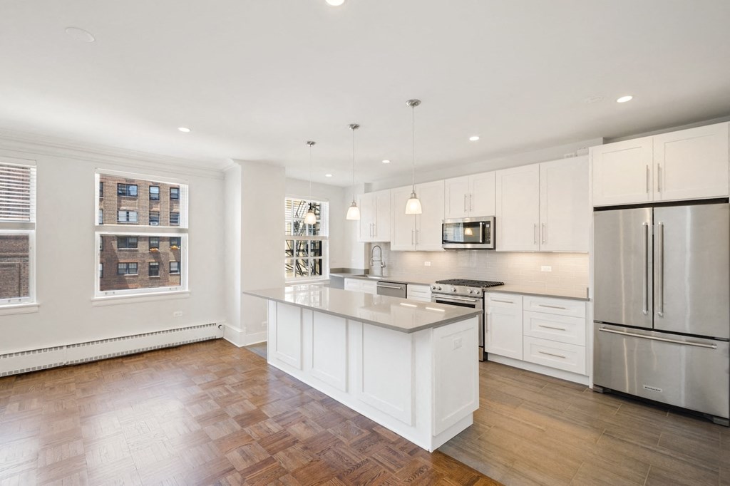 a white kitchen with a large island and stainless steel appliances