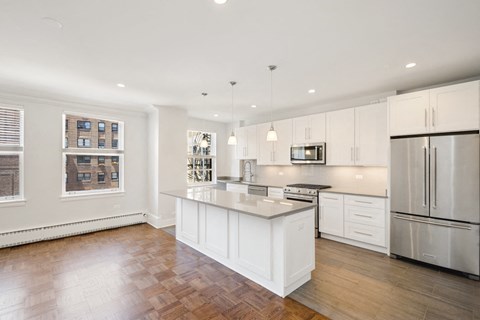 a white kitchen with a large island and stainless steel appliances