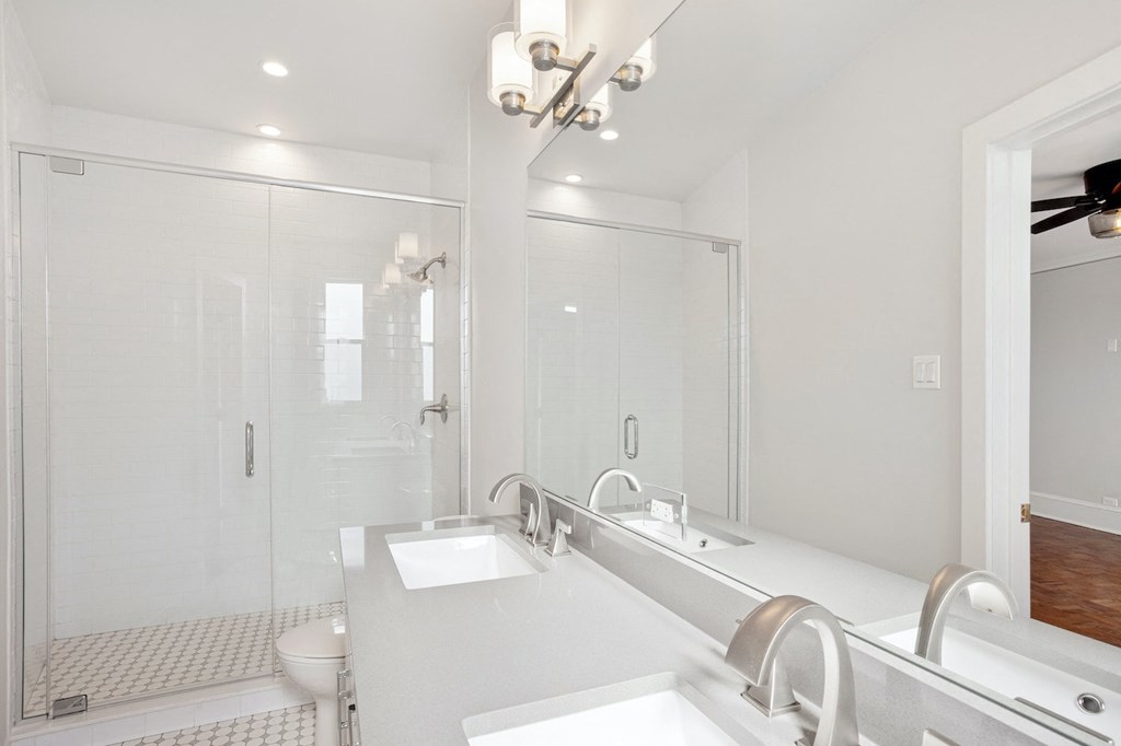 a white bathroom with two sinks and a shower