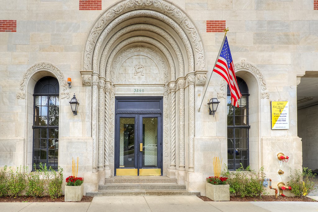the front of a building with a door and an flag