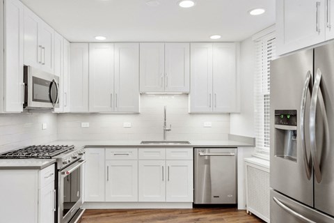 a white kitchen with stainless steel appliances and white cabinets