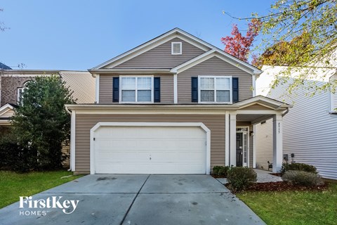 A house with a garage door and a tree in front of it.