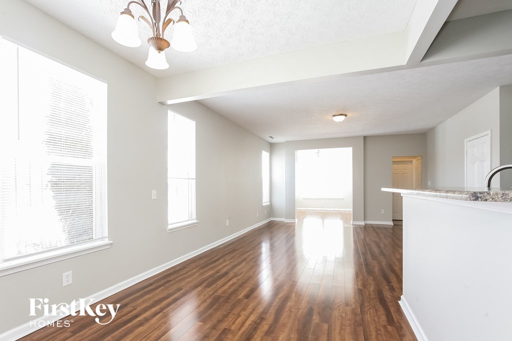 A spacious room with wooden floors and a large window.