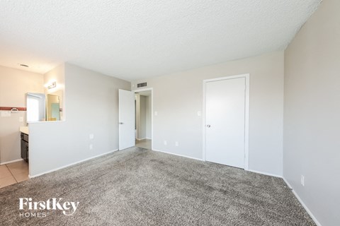 a spacious living room with carpet and white walls