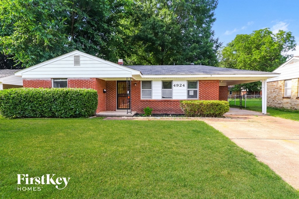 A brick house with a white roof and a green lawn in front.