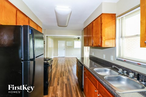 A kitchen with wooden cabinets and a black fridge.