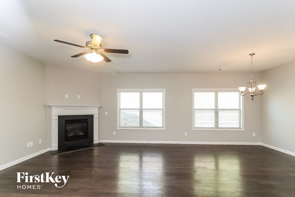A spacious living room with a fireplace and a chandelier.