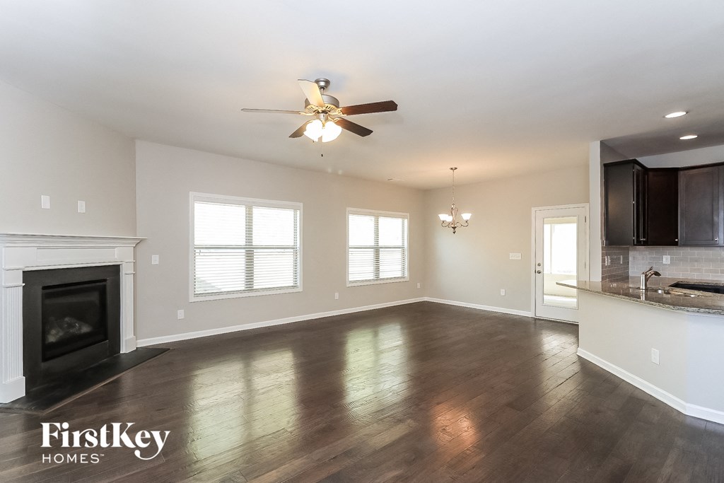 A spacious living room with wood flooring and a fireplace.