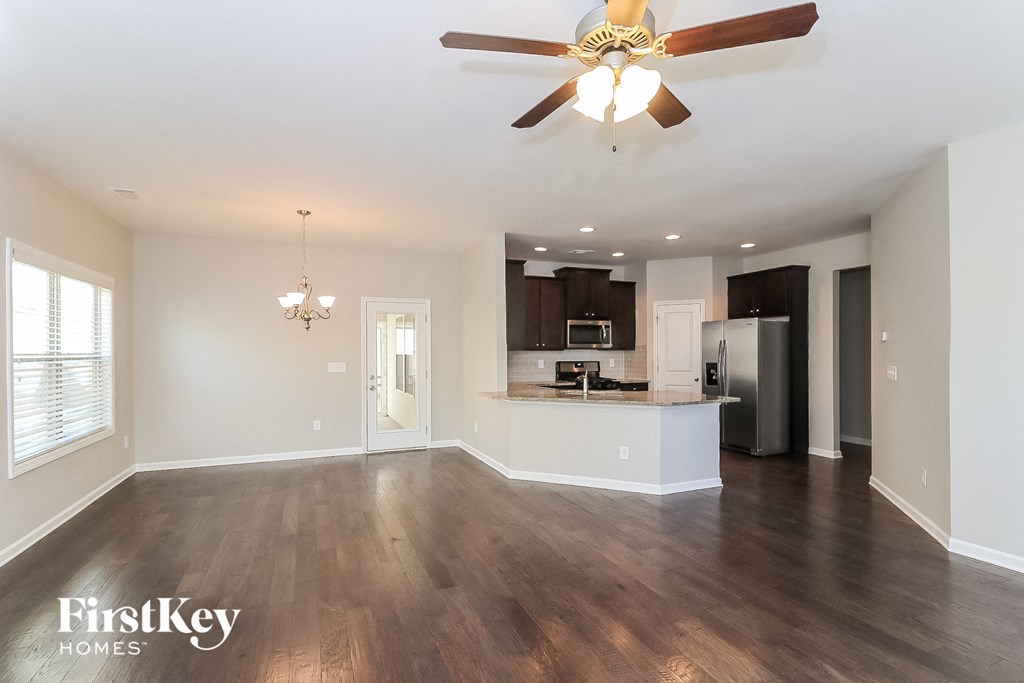 A spacious living room with a ceiling fan and hardwood floors.