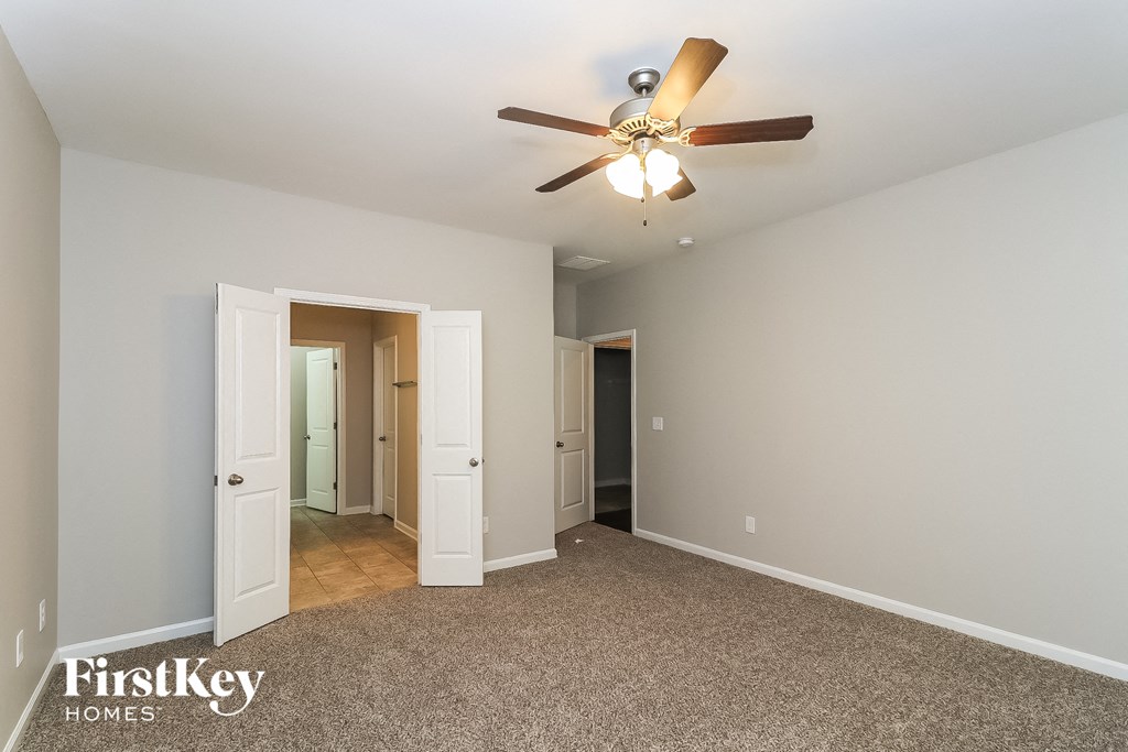 A spacious room with a carpeted floor and a ceiling fan.