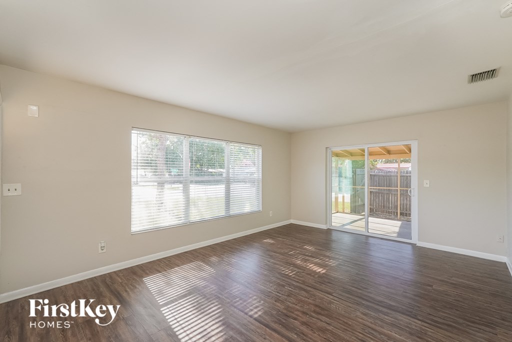 the living room of an empty house with a large window and wooden floors