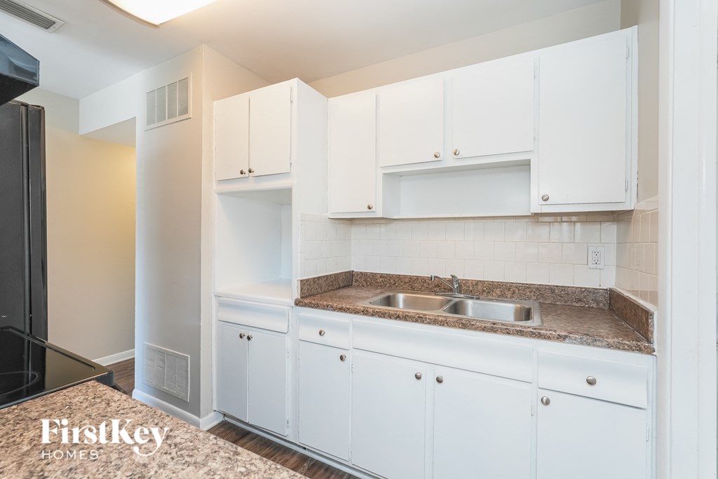 a kitchen with white cabinets and a stainless steel sink