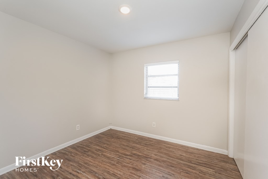 the living room of an apartment with a wood floor and white walls