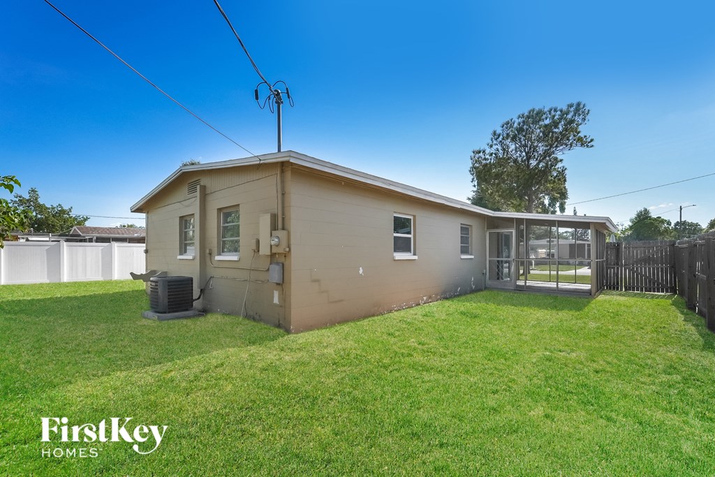 a small tan house with a grassy yard and a fence