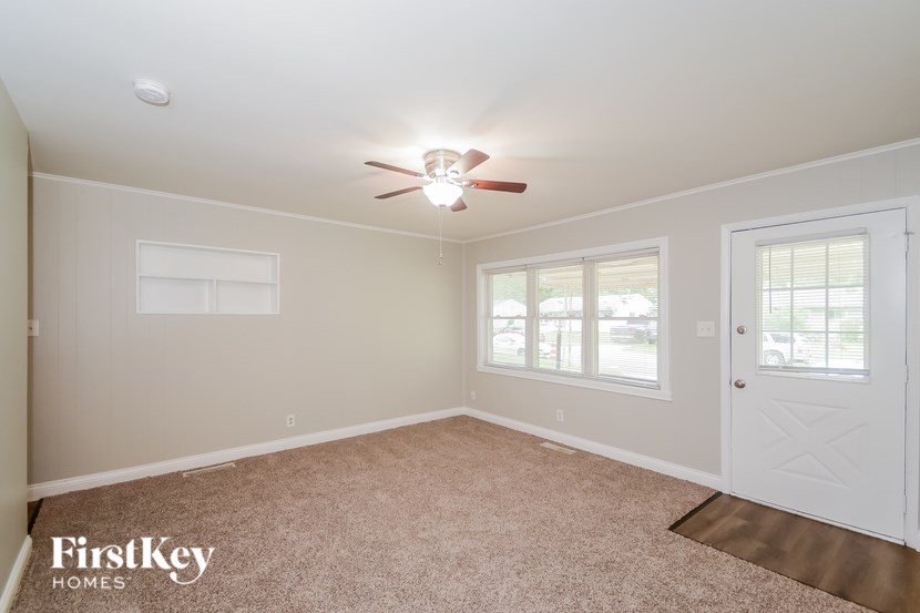 A room with a ceiling fan and a window with blinds.