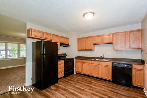 A kitchen with wooden cabinets and a black fridge.